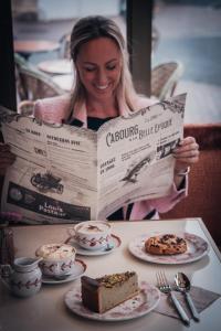 a woman sitting at a table reading a newspaper at Villa Henriette in Cabourg +88 photos