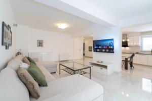 a white living room with a white couch and a table at Spacious modern One bedroom Apartment with Garden & SeaView in Rab