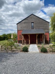 a gray barn with a red door and a driveway at La Maison des Champs in Ciney