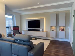 a living room with a blue couch and a flat screen tv at Haus Strandhafer in Wangerland