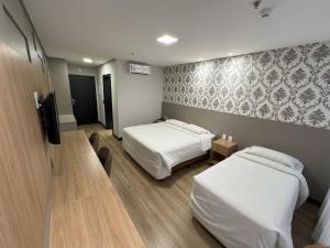 バウネアーリオ・コンボリウーにあるHotel das Américasのベッド2台とテレビのあるホテルの部屋