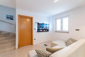 a living room with a white couch and a television at Private Detached House-2 Bedroom&3 Bathroom with Relaxing Garden Terrace-Grubelic House in Rab