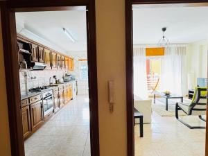 a kitchen with wooden cabinets and a living room at Cavado Pool Apartment in Fão