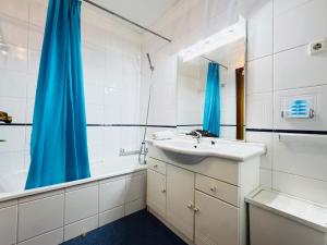 a bathroom with a sink and a blue shower curtain at Cavado Pool Apartment in Fão +18 photos