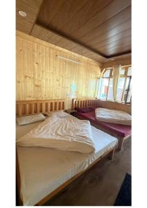 two beds in a room with wooden walls at Ekdantam Hotel and Restaurant in Uttarkāshi