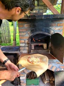 a man is cooking a pizza in a brick oven at Gárdonyi Ház in Sály
