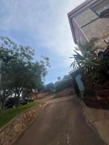 an empty road next to a house with a stone wall at Acactus in Kampala
