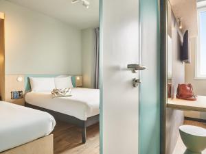 a hotel room with a bed and a bed and a room at ibis budget Nancy Laxou in Nancy