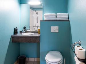 a blue bathroom with a toilet and a sink at ibis Budget Millau Viaduc in Millau +145 photos