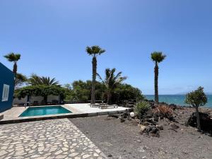 a swimming pool with palm trees next to the ocean at Cap-Azul in Porto Novo