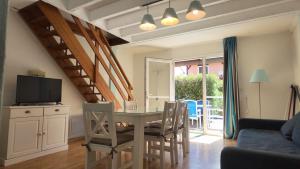 a living room with a dining room table with chairs at Résidence Mes Amours d'Enfants - Les Villas du Lac in Soustons