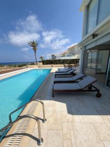 a row of lounge chairs next to a swimming pool at Nireas Crystal in Aglantzia