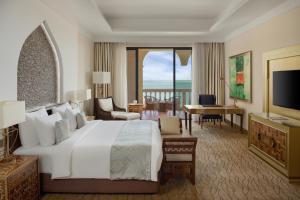 a bedroom with a large white bed and a living room at Marsa Malaz Kempinski, The Pearl in Doha