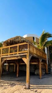 a wooden deck on the beach with a thatch roof at Hotel Portofino in Canoguero