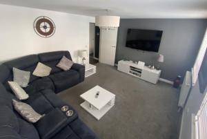 a living room with a black couch and a tv at Mossie Apartment in Ayr