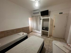a room with two beds and a flat screen tv at Pousada Saturnino in Hortolândia
