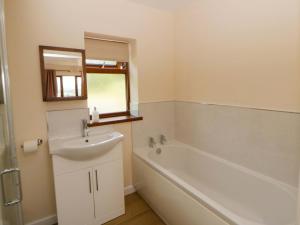 a bathroom with a sink and a tub and a mirror at Yr Onnen in Rhayader +30 photos