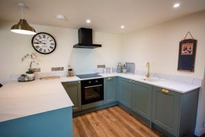 a kitchen with blue cabinets and a clock on the wall at Cosy Hideaway I Couples Break I Private Estate in Newborough +7 photos