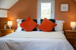 a bed with orange and white pillows and a window at Cosy Hideaway I Couples Break I Private Estate in Newborough