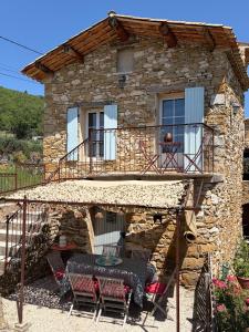 a stone house with a table and chairs in front of it at L'Arbre d'Alice in Ongles