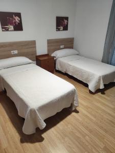 two beds sitting in a room with wooden floors at O marco da legua&camino de santiago in Piñor