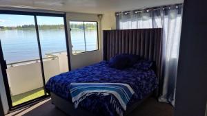 a bedroom with a bed with a view of the water at Old Willow Houseboats in Sasolburg