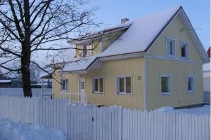 una casa amarilla con valla y techo cubierto de nieve en Guesthouse Valentini, en Otepää