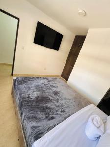 a bedroom with a bed and a flat screen tv at Aluna Hotel, Laureles Medellín in Medellín