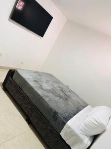 a bed in a white room with a picture on the wall at Aluna Hotel, Laureles Medellín in Medellín