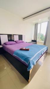 a bedroom with a large bed with purple sheets at Vinsroom Dua at Green Park in Seturan