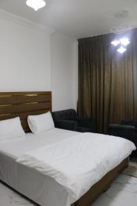 a bedroom with a large white bed and two chairs at Sea View Apartment with Balcony in Ajman 