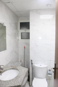 a white bathroom with a toilet and a sink at Sea View Apartment with Balcony in Ajman 