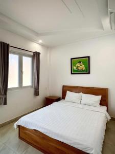 a bedroom with a large white bed with a window at Ven Song Riverside Hotel in Ho Tram