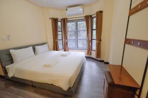 a bedroom with a large white bed and a window at พฤกษา วัลเลย์ รีสอร์ท in Ban Mak
