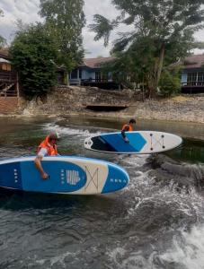 two people are on surfboards in the water at พฤกษา วัลเลย์ รีสอร์ท in Ban Mak
