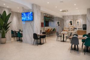 a restaurant with tables and chairs and a tv on the wall at Lh HOTELS in Milan