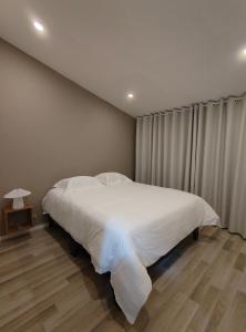 a bedroom with a white bed and a wooden floor at Andes 97 Guest House in Bogotá