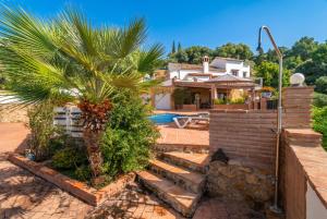 a house with a palm tree and a swimming pool at Cubo's Villa La Gitanilla in Mijas