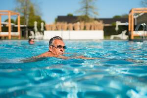 a man is swimming in a swimming pool at Resort Mooi Bemelen in Bemelen