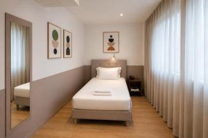 a small bedroom with a bed and a window at Lh HOTELS in Milan