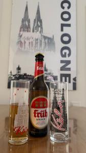 Eine Flasche Bier und zwei Gläser auf einem Tisch in der Unterkunft Villa Cologne - Apartments & Monteursquartiere in Meckenheim bei Köln in Meckenheim