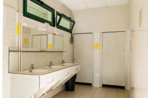 a bathroom with two sinks and a mirror at Camping Onlycamp le Clos Imbert in Thouars