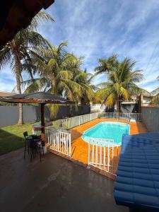 a swimming pool with a table and chairs and palm trees at Rancho Camiotto in Rubinéia