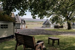 a park bench sitting under a tree with houses in the background at Carnethy Cabin in Kirknewton