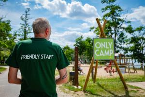 a man in a green shirt standing next to a playground at Camping Onlycamp le Clos Imbert in Thouars +11 photos