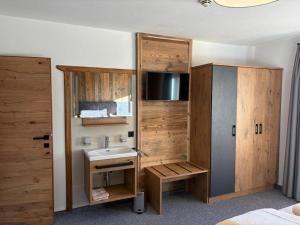a bathroom with a sink and a tv in a room at Alpenresort Panorama in Oberperfuss
