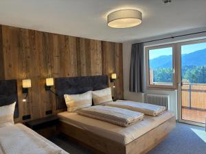a bedroom with two beds and a large window at Alpenresort Panorama in Oberperfuss