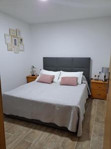 a bedroom with a large bed with two pink pillows at A Casinha - By Marketignite in Barreira