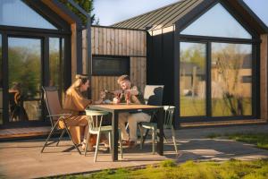 two people sitting at a table outside of a house at Vakantiehoeve Si-Es-An in Balkbrug