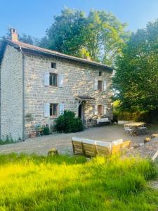 a stone house with two benches in front of it at L'Amour Toujours in Saint-Julien-le-Petit